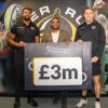 Celebrity Chef Michael Caines, with two Exeter Chiefs rugby players holding  a £3 million board 