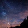 A night sky is shown with meteors streaking across it