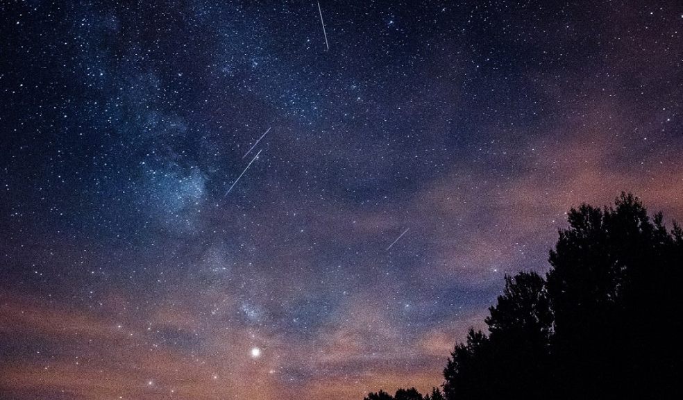 A night sky is shown with meteors streaking across it