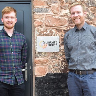 Two men in front of sign